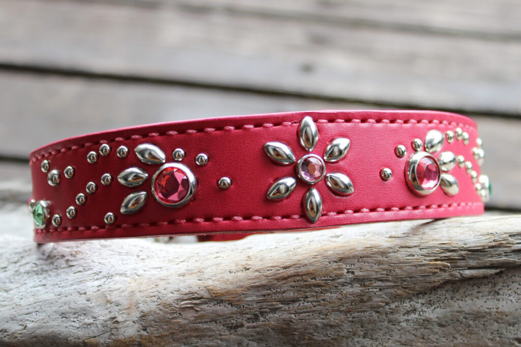 中型犬から大型犬用のビビットピンクの革首輪。中央に花の形をしたスタッズで装飾され、両脇には流れるようなデザインのスタッズが飾り付けられています。