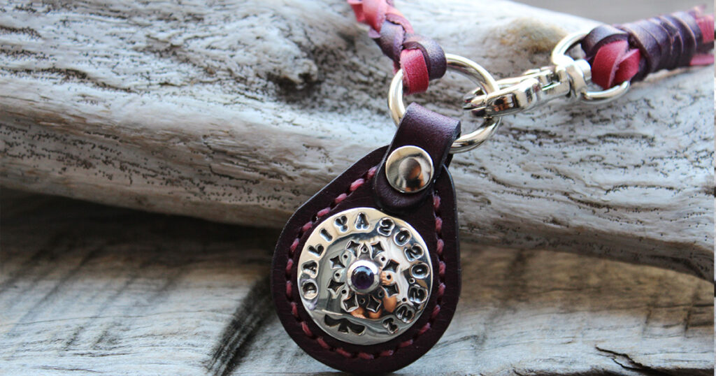 ビビットピンクと紫の編み込みネックレスタイプのネームタグ。タグ部分は紫革で、シルバーコンチョ（KOAアメジストの石）が飾られています。