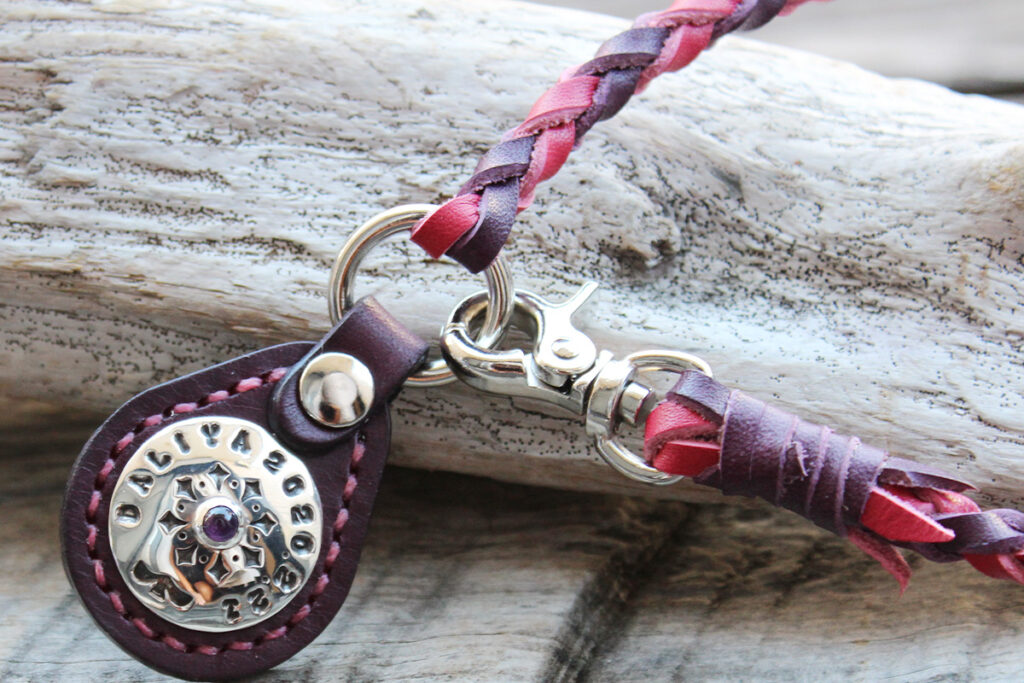 ビビットピンクと紫の編み込みネックレスタイプのネームタグ。タグ部分は紫革で、シルバーコンチョ（KOAアメジストの石）が飾られています。タグ部分の画像